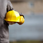 The builder holds a helmet in his hands